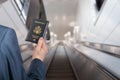 Man businessman in a blue suit with suitcase holding american passport with boarding pass on the airport escalator. Royalty Free Stock Photo