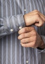 Close up detail of man`s hands buttoning shirt cuffs. Businessman getting ready for work. Men`s clothing apparel.