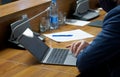 A man - a businessman, official, accountant or lawyer, uses the touchpad of a small laptop while sitting at a desk in the office.