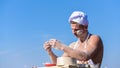 Man on busy face wears cooking hat and apron, sky on background. Baker concept. Cook or chef with muscular Royalty Free Stock Photo