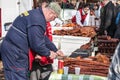 Man, a butcher, slicing kulen sausage on a stall on the market of Kacarevo.