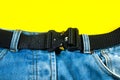 A man buttoned a black cloth belt on jeans. Modern men`s waistband with dark matted metal buckle Royalty Free Stock Photo