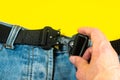 A man buttoned a black cloth belt on jeans. Modern men`s waistband with dark matted metal buckle Royalty Free Stock Photo