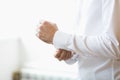 Man buttons cuff link on cuffs sleeves luxury white shirt. Close up of man hand wears white shirt and cufflinks. Groom