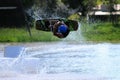 Man cable park wakeboard helmet impact vest boots good style. slippery cylindrical module in a lagoon with green grass backgroun