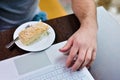 Man in cafe at the table holds his hand near the laptop