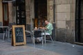 A man at a cafe table is reading a newspaper.