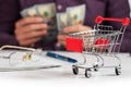 Man calculates the budget. Shopping cart a on table with calculator and paper and mohey in hadns Royalty Free Stock Photo