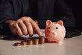 Man calculates profit, piggy bank with stack of coins at the desk. Savings and investment concept Royalty Free Stock Photo