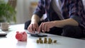 Man calculating money, saving coins in piggy bank, family budget planning