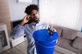 Man Calling Plumber While Leakage Water Falling Into Bucket Royalty Free Stock Photo