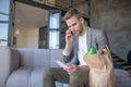 Man calling wife after buying food while sitting in living room