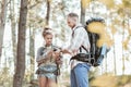 Man calming his appealing woman after being lost in forest with backpacks