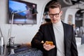 man came to business meeting, stand using smartphone, looking for colleague