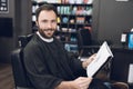 A man sits in a barber`s chair in a man`s barbershop, where he came to cut his hair. Royalty Free Stock Photo