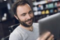 A man looks at the tablet in the barber`s chair in a man`s barbershop. Royalty Free Stock Photo