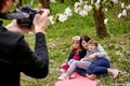 A man with a camera photographs a young woman with a smiling boy and girl. Against the background of green grass and forest Royalty Free Stock Photo