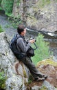Man with camera on the rock over mountain river. Royalty Free Stock Photo