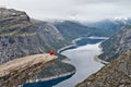 Man with camera sitting on Trolltunga rock and makes the photo with the Norwegian mountain landscape Royalty Free Stock Photo