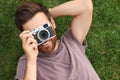 Man with camera taking photo on green grass, top view. Interesting hobby