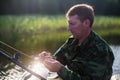 Man in camouflage fishing rod on the river on a rubber boat. Hobby. Royalty Free Stock Photo