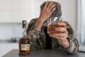 A man in camouflage suffers from depression after returning from the army. He uses alcohol and narcotic tablets. He is