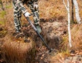 Man in a camouflage suit, with military colors, metal detector looking for scrap metal, precious metals and treasures in autumn