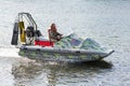 Man in camouflage uniforms and life jacket riding airboat along water surface. Inflatable rubber air boat sail on river