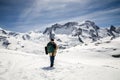 A man in camouflage winter coat and backpack standing in front of the background of snow mountain. Royalty Free Stock Photo