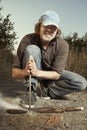 Man camping in nature making fire with wood stick friction by hands