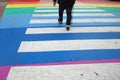 A man is crossing a zebra crossing in rainbow colors Royalty Free Stock Photo