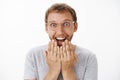 Man cannot hide happiness and excitement receiving awesome news holding palms above mouth smiling broadly with