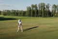 Man in cap holding golf club and hitting ball on green lawn Royalty Free Stock Photo