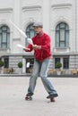 A man in a cap juggles with clubs on the street