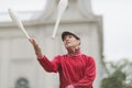 A man in a cap juggles with clubs on the street