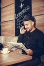 Man with cap reading the newspaper and talking