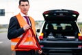 Man with car breakdown erecting warning triangle Royalty Free Stock Photo