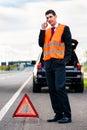 Man with car breakdown erecting warning triangle Royalty Free Stock Photo