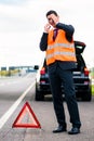 Man with car breakdown erecting warning triangle Royalty Free Stock Photo