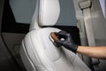 Man car detailing studio worker cleaning car leather seat with a brush.