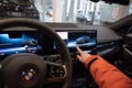 man in car driving BMW i5 eDrive40, manipulates electronic display, digital panel, cockpit modern EV, male hands on steering wheel
