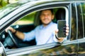 Man in car driving showing smart phone display screen