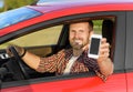 Man in car driving showing smart phone