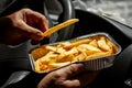 Man in the car eat yummy french fries in aluminium foil tray. Fast food o street food takeaway service concept