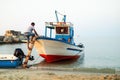 Man carefully stepping into a small, wooden boat in a lake Royalty Free Stock Photo