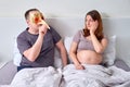 Man in carnival mask and pregnant woman lying in bed Royalty Free Stock Photo