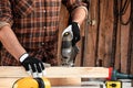 A man carpenter cuts a wooden beam using an electric jigsaw, male hands with an electric jigsaw closeup. Work with wood Royalty Free Stock Photo