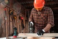 A man carpenter cuts a wooden beam using an electric jigsaw, male hands with an electric jigsaw closeup. Work with wood