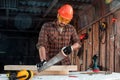 A man carpenter cuts a wooden beam using a handsaw, male hands with a saw closeup. Work with wood