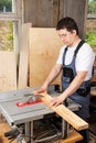 A man carpenter saws a wooden Board on a woodworking machine